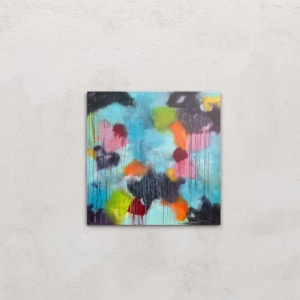 Et maleri med mange kulørte farver hænger på en hvid væg