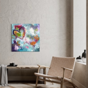 Maleri med kulørte farver og et stort hjerte hænger på væggen i en entre